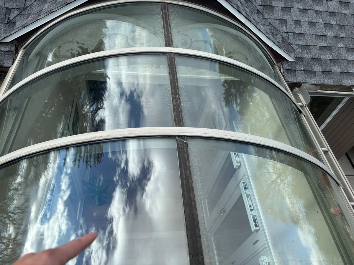 Curved conservatory glass cleaned to a clear reflection of the sky